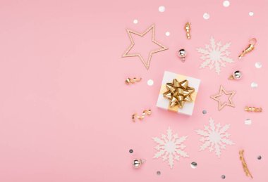 Noel tebrik kartı şablonu. Altın ve gümüş madalyalar, şenlikli hediyeler, pembe arka planda kar taneleri. Xmas, kış, yeni yıl konsepti. Düz konum, üst görünüm, kopyalama alanı.