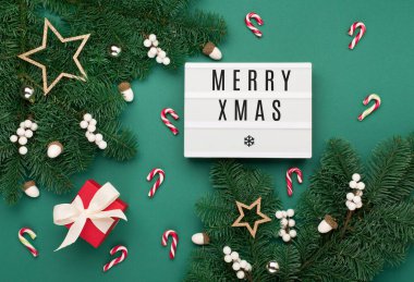Mutlu Xmas metinleri hediye kutulu beyaz ışık kutusu, tatil altın madalyaları, yeşil Noel ağacı dallarında meşe palamutları. Düz konum, üst görünüm, kopyalama alanı. Şenlikli kış zamanı.