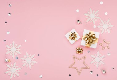 Noel tebrik kartı şablonu. Altın ve gümüş madalyalar, şenlikli hediyeler, pembe arka planda kar taneleri. Xmas, kış, yeni yıl konsepti. Düz konum, üst görünüm, kopyalama alanı.