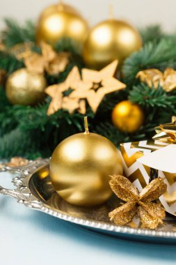 Mavi masadaki Noel çelengi, üst manzara. Altın mumlu modern noel çelengi, yeşil dallar ve mavi arka planda altın yıldızlar. Kış tatili zamanı.