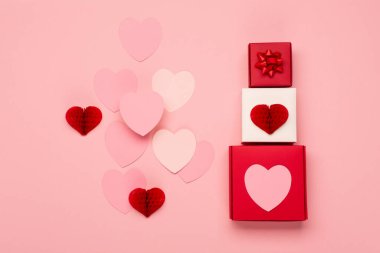 Pembe kağıt kalpler ve pastel pembe arka planda kırmızı hediye kutuları. Sevgililer Günü konsepti. Düz konum, üst görünüm, kopyalama alanı. Sevgililer Günü için bayram tebrik kartı, doğum günü, kadın ya da anneler günü.