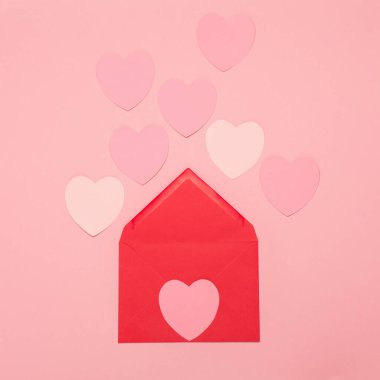 Pembe kağıt kalpler ve pastel pembe arka planda kırmızı boş bir zarf. Sevgililer Günü konsepti. Düz konum, üst görünüm, kopyalama alanı. Sevgililer Günü için bayram tebrik kartı, doğum günü, kadın ya da anneler günü