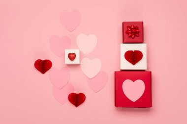 Pembe kağıt kalpler ve pastel pembe arka planda kırmızı hediye kutuları. Sevgililer Günü konsepti. Düz konum, üst görünüm, kopyalama alanı. Sevgililer Günü için bayram tebrik kartı, doğum günü, kadın ya da anneler günü.