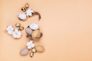 Bej renkli pastel arka planda paskalya yumurtaları ve metin için boşluk. Düz konum resim kompozisyonu, üst görünüm. Paskalya dekorasyonu, minimalist yumurta tasarımı, modern tasarım şablonu.