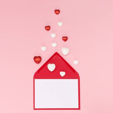 Parlayan kalpler, boş bir kart ve pembe arka planda bir zarf. Sevgililer Günü konsepti. Düz konum, üst görünüm, kopyalama alanı. Sevgililer Günü için bayram tebrik kartı, doğum günü, kadın ya da anneler günü.