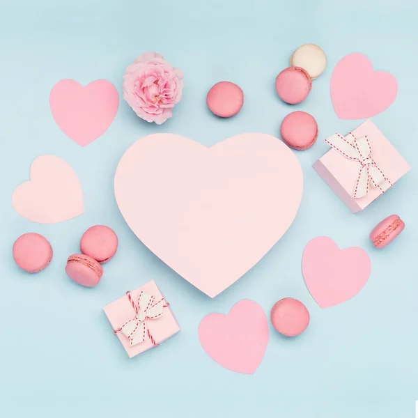 Valentines Day card. Pink gifts with ribbon and macaron macaroon cookie on blue background. 8 March, Womens Mothers Valentines Day, Birthday. Flat lay, top view, copy space.