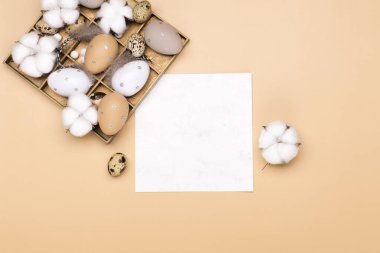 Paskalya yumurtaları ve bej renkli pastel arka planda pamuk çiçekleri, yazı için yer. Paskalya dekorasyonu, minimalist yumurta tasarımı, modern tasarım şablonu. Mutlu Paskalya bayramı kartları, üst manzara.