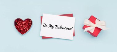 Sevgililer Günü konsepti. Hediye kutusu, kırmızı parıltılı kalp ve mavi arka planda boş zarf. Düz konum, üst görünüm, kopyalama alanı. 8 Mart, Sevgililer Günü Anneler Günü, Doğum günü bayramı kartı.