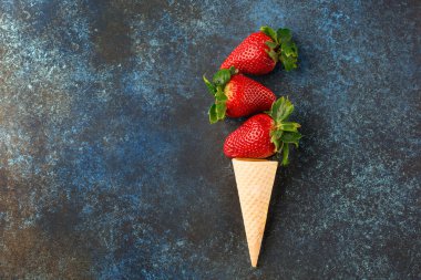 Waffle külahında taze çilek, sağlıklı yaz yemeği konsepti, üst manzara, koyu mavi ahşap arka plan..