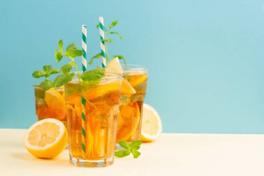 Geleneksel ev yapımı buzlu çay, limon, nane ve uzun bardaklarda buz. Mavi arka planda soğuk yaz içeceği. Sağlıklı yaz yemekleri konsepti. Seçici odak, boşluğu kopyala. 
