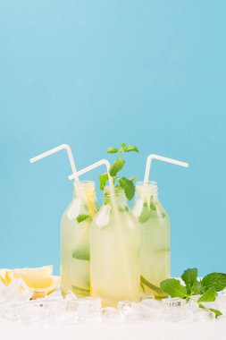 Taze ev yapımı limonata ya da naneli mojito kokteyli. Soğuk, ferahlatıcı içecek ya da beyaz ve mavi arka planda buzlu içecek.