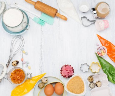 Paskalya için tatlı pişirme konsepti. Merdaneli yemek pişirme, yumurta çırpma, çırpma, kurabiye kesme, şeker serpiştirme, un. Rustik beyaz tahta arkaplan, üst görünüm kopyalama alanı.