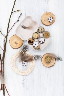 Zero waste Easter background on white wooden table. Quail Easter eggs, natural Spring decorations, cotton flowers and pussy willow branches. Top view, copy space. Eco friendly lifestyle.