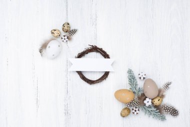 Paskalya bıldırcın yumurtaları, yuva ve pamuk çiçekleriyle beyaz ahşap zemin üzerinde el yapımı Paskalya kompozisyonu. Üst görünüm, kopyalama alanı, düz yatış. Paskalya bayramı tebrik kartı.. 