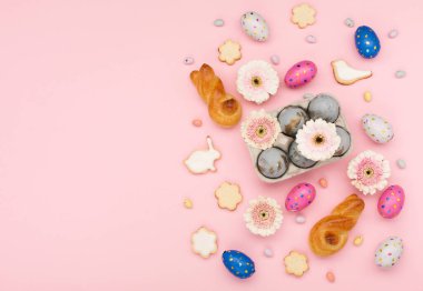 Mutlu Paskalya bayramı tebrik kartları. Ev yapımı Paskalya tavşanı, şekerli kurabiyeler, çikolatalı yumurtalar, pastel pembe arka planda çiçekler. Bayramlık Paskalya kahvaltısı konsepti. Boşluğu kopyala, üst görünüm.