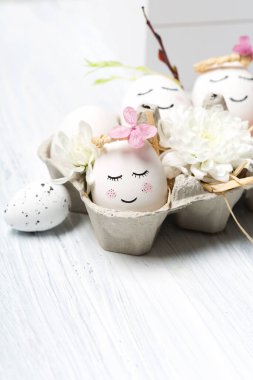 Beyaz tatlı yumurtalar, ağaç dalları, bıldırcın tüyleri ve beyaz ahşap arka planda bahar çiçekleri olan sıfır atık Paskalya konsepti, kopyalama alanı. Paskalya bayramı tebrik kartı..