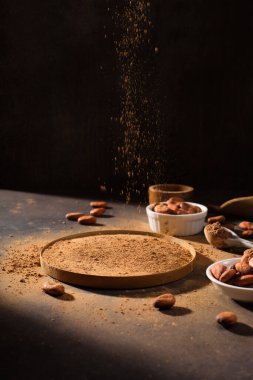İçinde organik kakao tozu ve koyu kırsal ahşap arka planda aromatik çiğ kakao çekirdekleri olan bir kâse. Seçici odak, uzayı kopyala. Süper Beyin Gıda Konsepti.