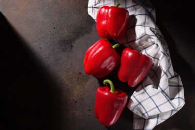 Yemek pişirme geçmişi. Taze kırmızı biber ve koyu kırsal ahşap arka planda tekstil beyazı mavi havlu. Üst görünüm, boşluğu kopyala. Taze sağlıklı yiyecekler, vejetaryen diyeti.. 