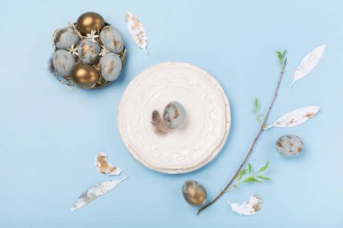 Paskalya bayramı tebrik kartı geçmişi. Mavi altın yumurtalı Paskalya Süslemesi, bıldırcın tüyleri, mavi arka planda çiçekler. Paskalya kartı konseptin kutlu olsun. Boşluğu kopyala, üst görünüm.