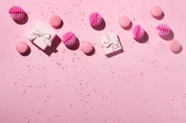 Mutlu yıllar ya da parti geçmişi. Tatlı keklerle, kurabiyelerle, serpiştirmelerle, pembe hediye kutularıyla ve pembe arka planda kağıt dekorasyonlarla bezenmiş düz bir kompozisyon. Üst görünüm, boşluğu kopyala. Şenlikli tatil konsepti.