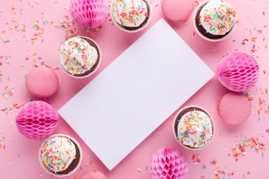 Doğum günü, kadın ya da anneler günü için bayram tebrik kartı. Boş beyaz, hediye kutusu, kağıt süslemeler ve pembe serpiştirilmiş kekler. Düz konum, üst görünüm, kopyalama alanı.