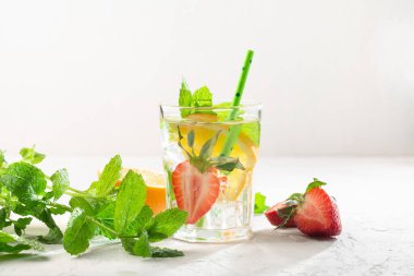 Taze meyve, limonata içecekler, serinletilmiş su. Taze çilekli, portakallı, limonlu ve naneli bardaklar. Beyaz güneş arkaplanı, kopyalama alanı.