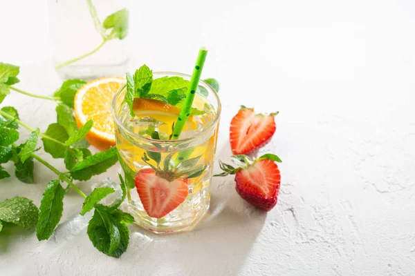 Taze meyve, limonata içecekler, serinletilmiş su. Taze çilekli, portakallı, limonlu ve naneli bardaklar. Beyaz güneş arkaplanı, kopyalama alanı.