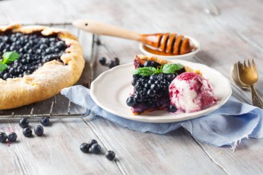 Ev yapımı yabanmersini turtası, dondurma ve beyaz ahşap arka planda taze nane, seçici odaklanma..