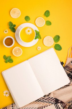 Sarı zemin üzerinde nane, zencefil, limon ve bal bulunan papatya çiçeği çayı. Sonbahar ya da kış mevsimi için baharatlı tıbbi çay. Düz yatış, üst görünüm.