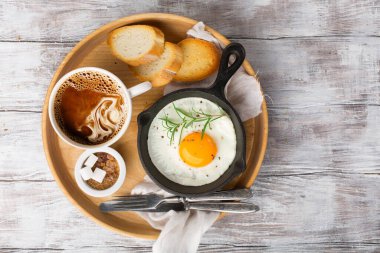 Bir kap sahanda yumurta, çıtır baget, meyve reçeli ve beyaz ahşap arka planda bir fincan kahve. Üst görünüm, boşluğu kopyala. Kahvaltı zamanı konsepti.
