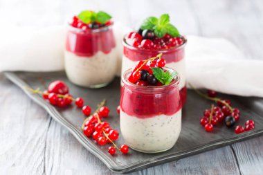 Kahvaltı için kavanozda beyaz ahşap arka planda katmanlı böğürtlen ve chia tohumlu smoothie. Seçici odak, uzayı kopyala. Sağlıklı gıda yaz tatlısı konsepti.