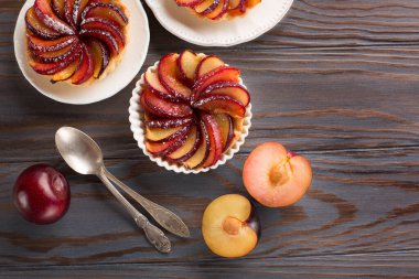 Ahşap arka planda erik ve esmer şekerli ev yapımı tart. Üst manzara, başa çıkma alanı. Yaz sonbahar yemek tatlısı konsepti.