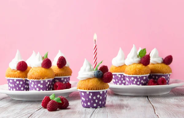 节日生日香草杯蛋糕与新鲜的覆盆子 奶油和点燃的蜡烛粉红背景 选择性焦点 复制空间 — 图库照片