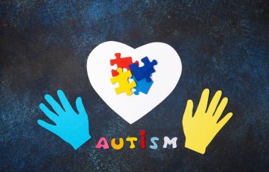 Otizm Farkındalık Günü tasarımı mavi arka planda renkli ve beyaz yapboz parçaları, basit sembolik düzen. destek ve anlayış, üst görünüm, metin için boşluk.