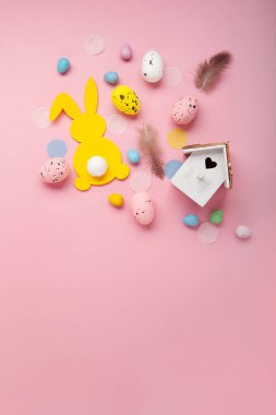 Paskalya bayramı kartı. Neşeli tavşan, boyanmış yumurta, bahar çiçekleri, açık pembe arka planda dekoratif elementler.