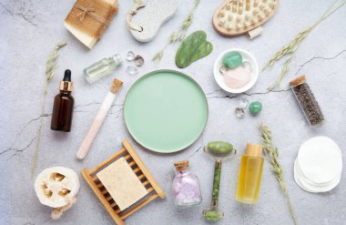 Sıfır atık sürdürülebilir kozmetik cilt bakım ürünleri ve gri taş arka planda çevre dostu banyo aksesuarları. İyileştirici kristaller, yeşil kuvars masajcı, gua sha.