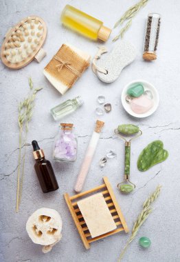 Sıfır atık sürdürülebilir kozmetik cilt bakım ürünleri ve gri taş arka planda çevre dostu banyo aksesuarları. İyileştirici kristaller, yeşil kuvars masajcı, gua sha.