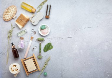 Sıfır atık sürdürülebilir kozmetik cilt bakım ürünleri ve gri taş arka planda çevre dostu banyo aksesuarları. İyileştirici kristaller, yeşil kuvars masajcı, gua sha.