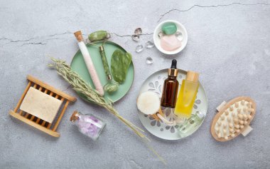 Sıfır atık sürdürülebilir kozmetik cilt bakım ürünleri ve gri taş arka planda çevre dostu banyo aksesuarları. İyileştirici kristaller, yeşil kuvars masajcı, gua sha.