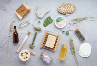 Sıfır atık sürdürülebilir kozmetik cilt bakım ürünleri ve gri taş arka planda çevre dostu banyo aksesuarları. İyileştirici kristaller, yeşil kuvars masajcı, gua sha.