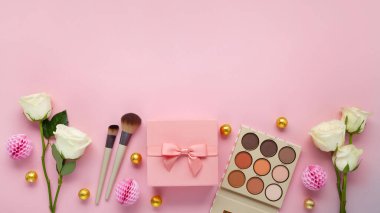 Dekoratif kozmetik ürünleri, pembe hediye kutusu ve pastel pembe arka planda beyaz güller Anneler Günü tebrik kartı için.