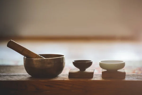 Tibetan singing bowl for meditation and mindfulness. Little cup of tea on on a wooden surface