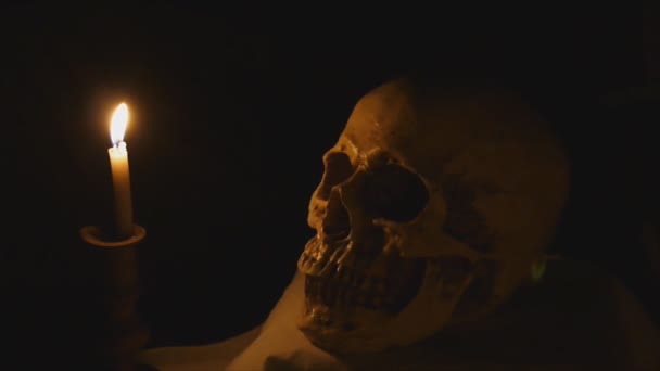 Людський череп і палаюча свічка — стокове відео