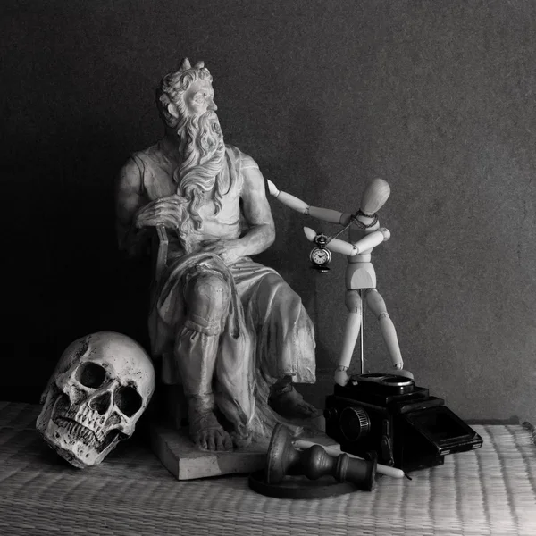 Still life of moses statue ,skull,wooden figure on mat — Stock Photo, Image