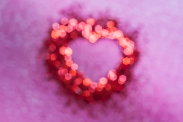 Flou de bokeh rouge avec forme de coeur à l'intérieur sur fond rose — Photo