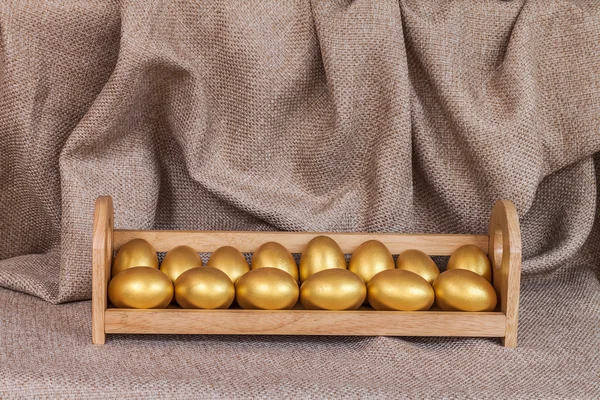 Oeuf de Pâques en or dans une étagère en bois — Photo