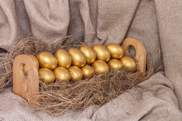 Oeuf de Pâques en or sur le foin dans une étagère en bois — Photo