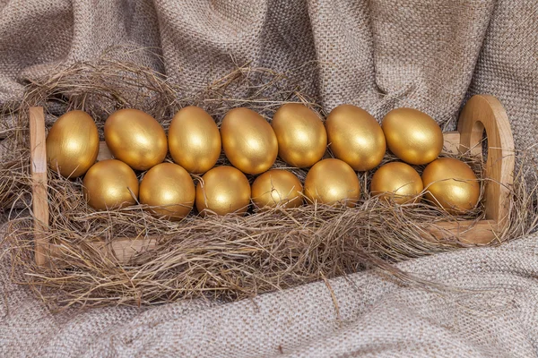 Oeuf de Pâques en or sur le foin dans une étagère en bois — Photo