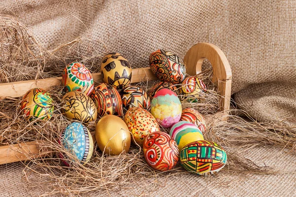Barevný malovaný velikonoční vajíčko na seno v dřevěné police — Stock fotografie