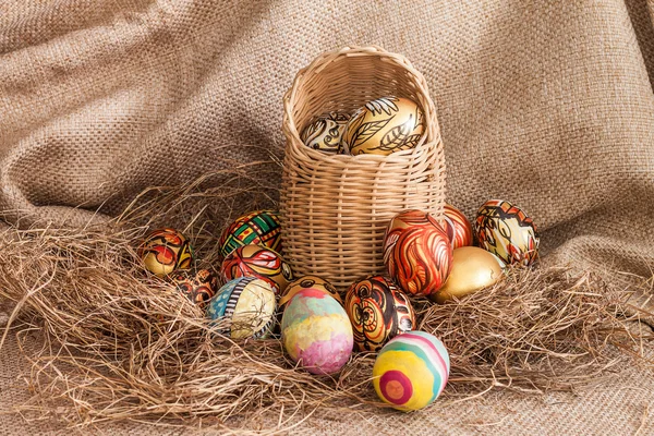 Renkli hasır sepet saman üzerinde Paskalya yumurta boyalı — Stok fotoğraf